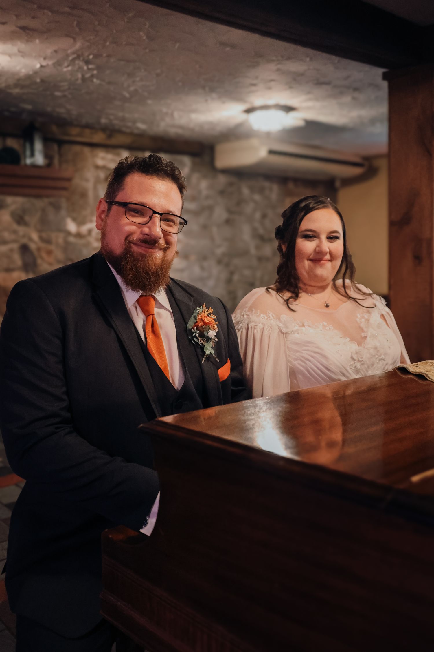 A couple signs wedding documents at a rustic venue with exposed brick walls and wooden details.