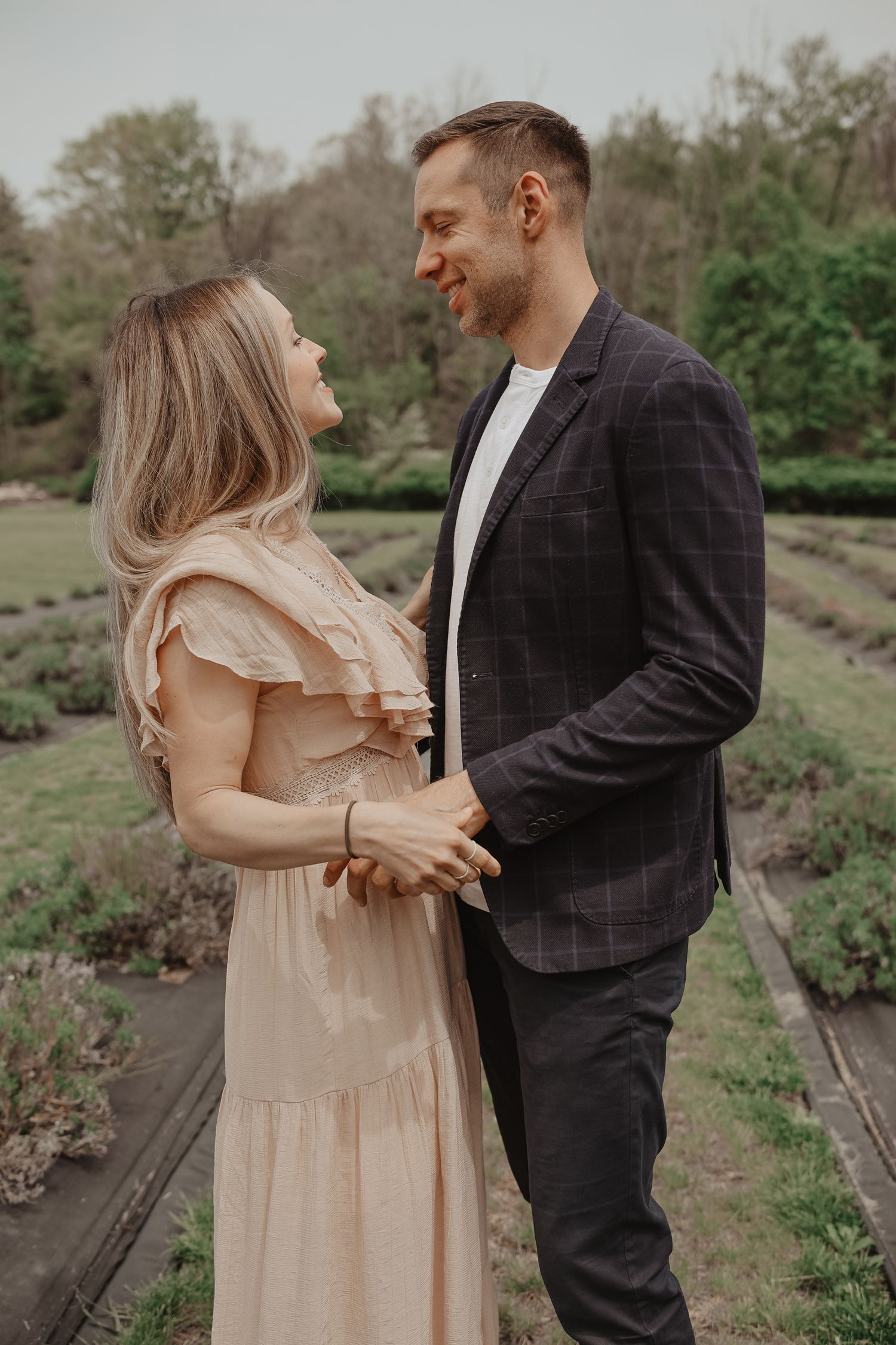 A couple in formal attire shares an intimate moment in a garden setting during a photo session.