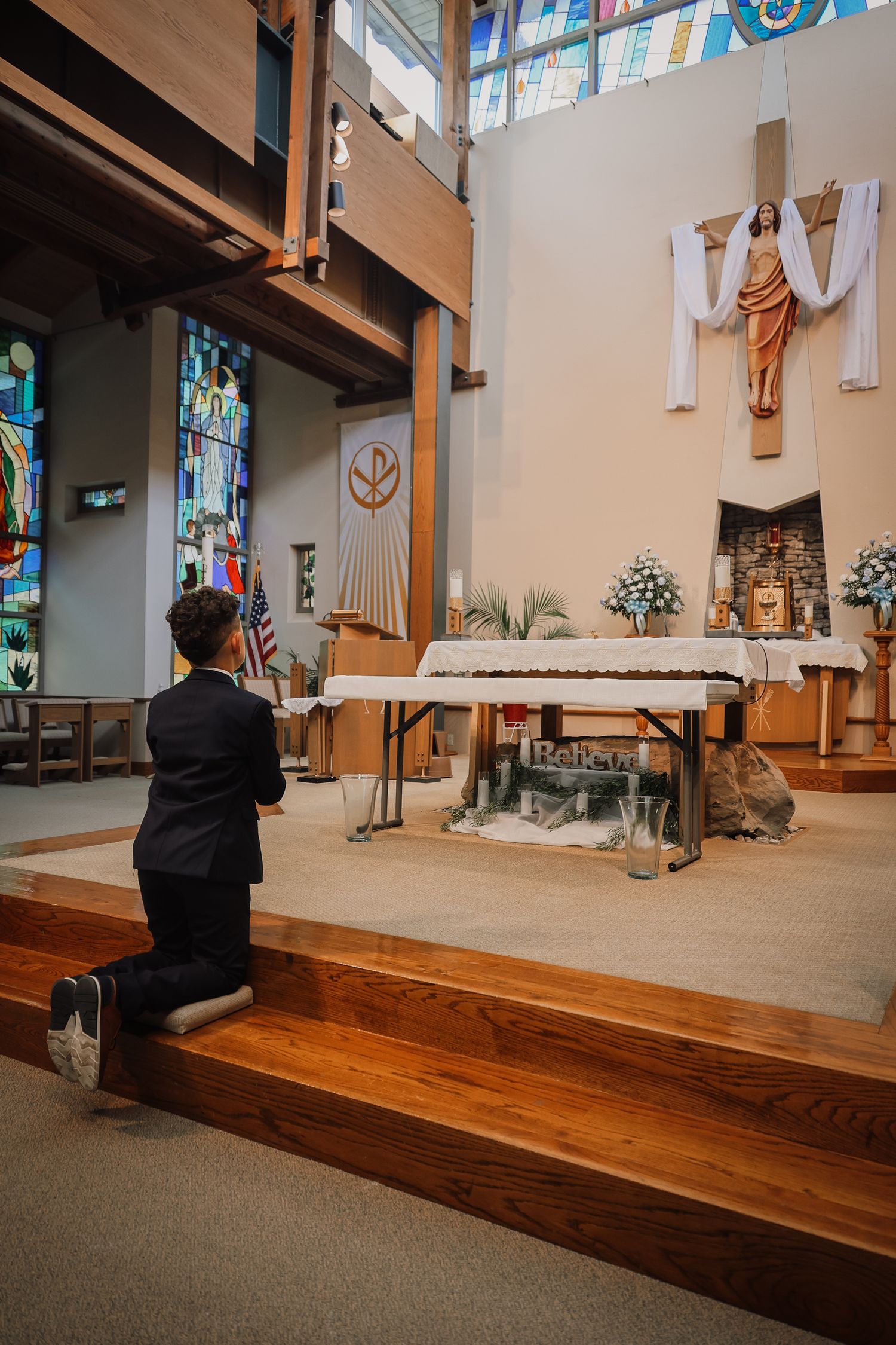 Interior view of a modern church sanctuary with wooden pews and religious artwork showing different angles and details.