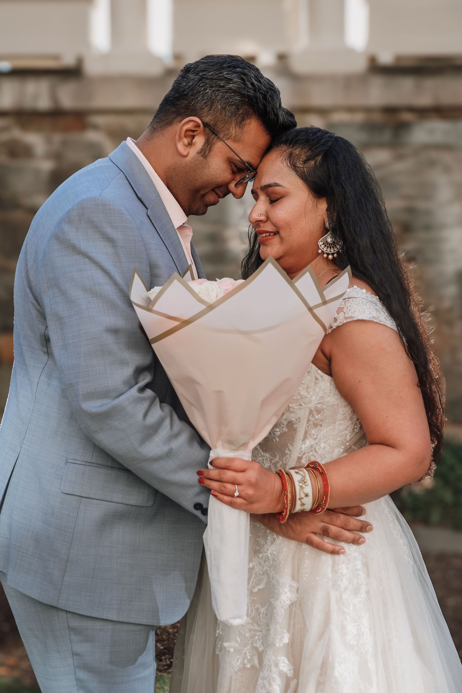 A romantic wedding photo series showing tender moments between a couple in formal attire against a stone wall backdrop.