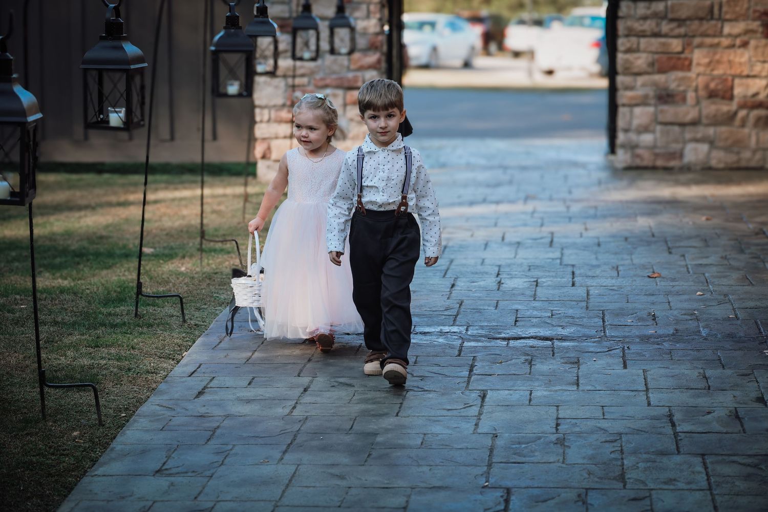 A couple walks along a stone pathway surrounded by lanterns at their wedding venue.