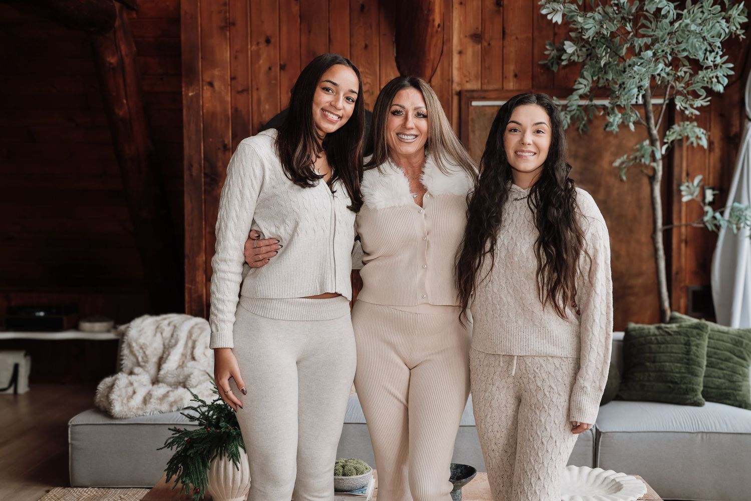 A group wearing matching cream-colored outfits poses together in an elegant indoor setting with natural lighting.