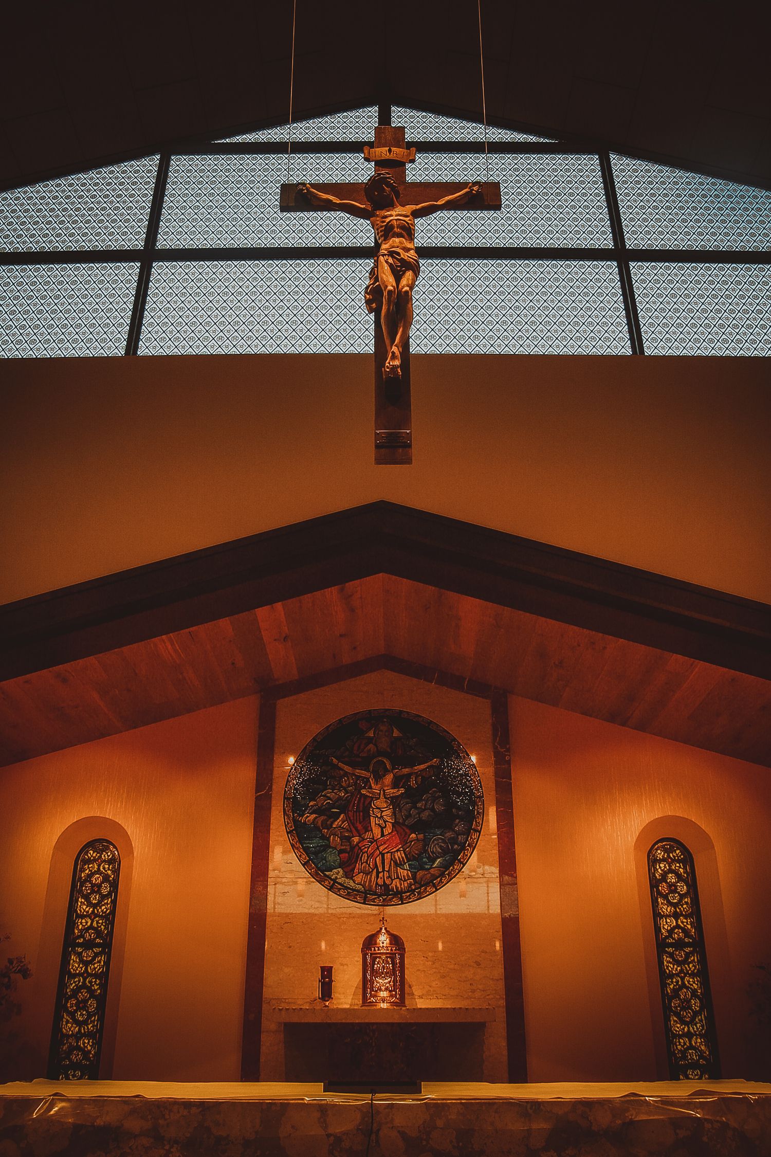 A panoramic sequence showing a crucifix and religious artwork on an illuminated church altar wall at dusk.