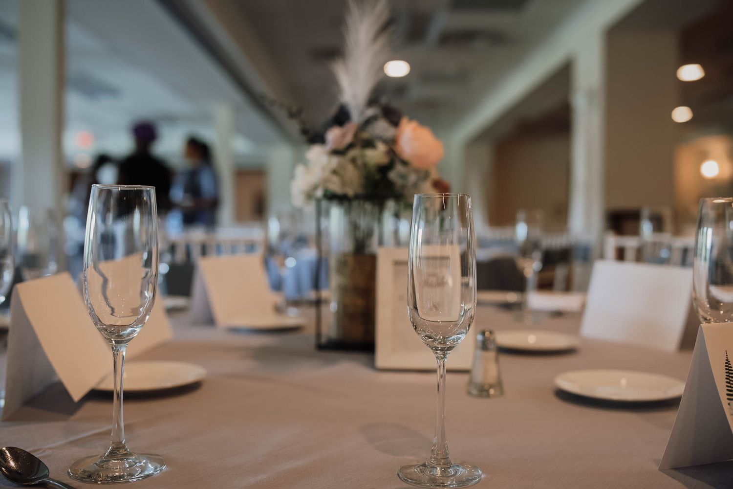 Elegant wedding reception table setting with champagne flutes, place cards, and floral centerpiece.