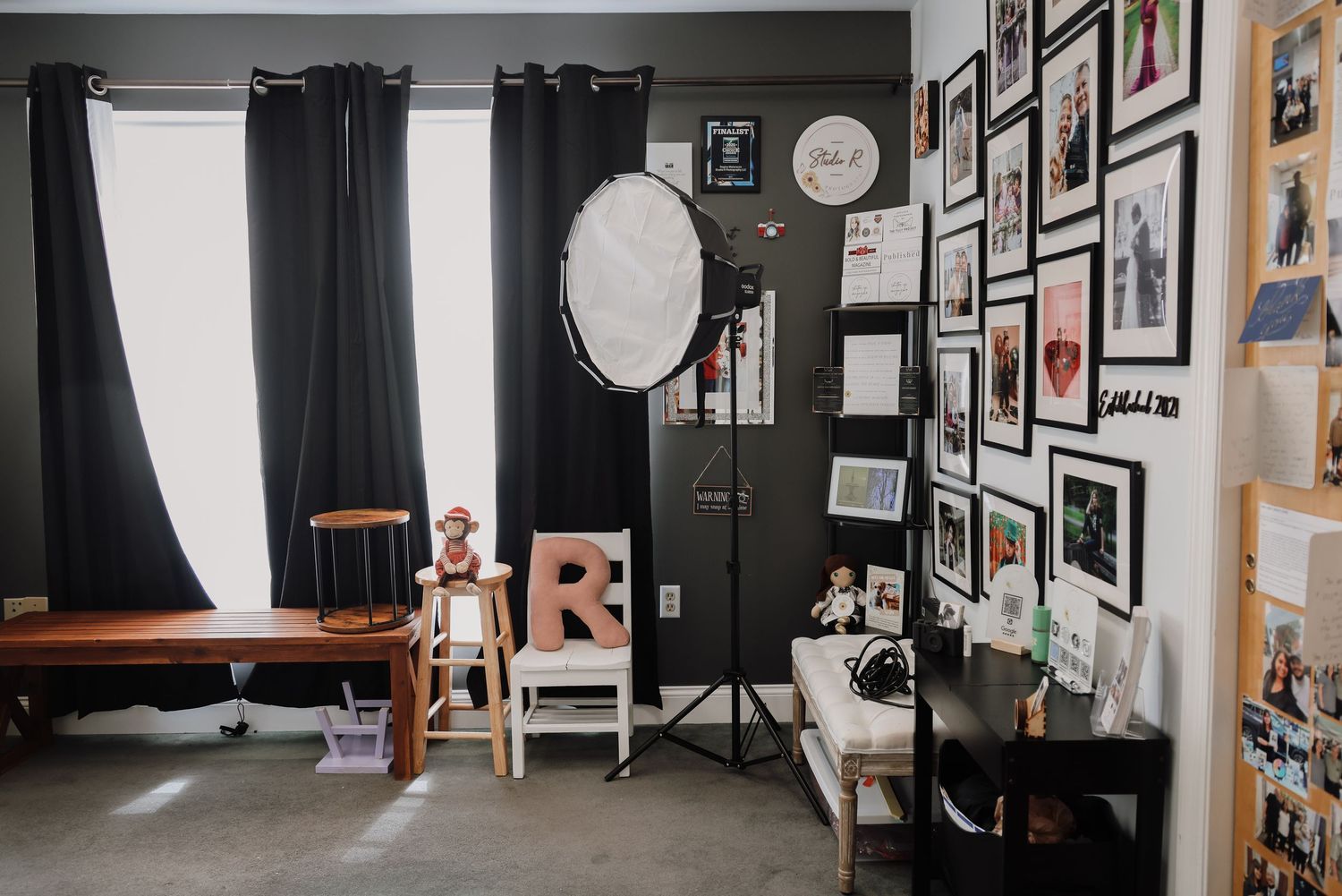 A panoramic view of a modern photography studio with black walls, framed photos, and professional lighting equipment.