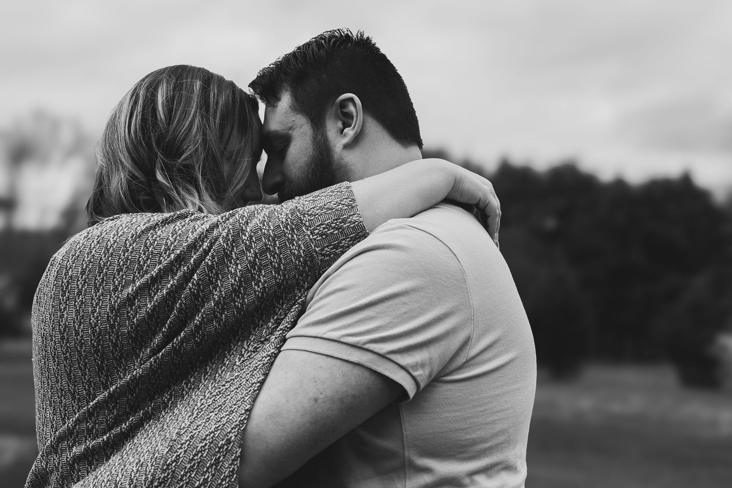 A series of black and white romantic photos showing a couple embracing outdoors in a tender moment.