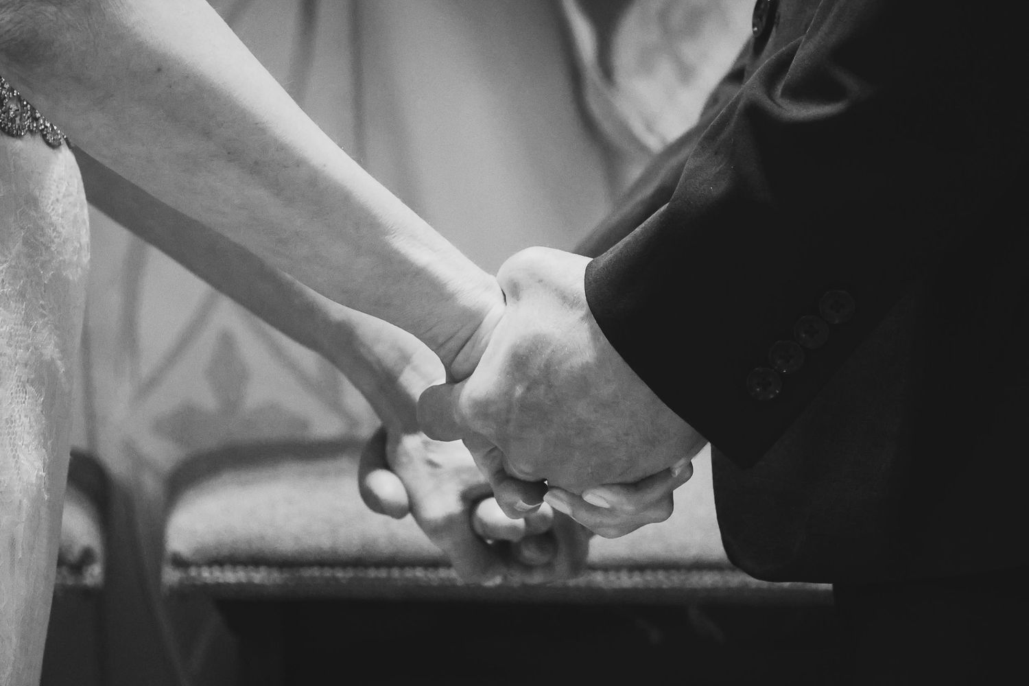 Black and white close-up photograph of two hands clasped together in an intimate moment.