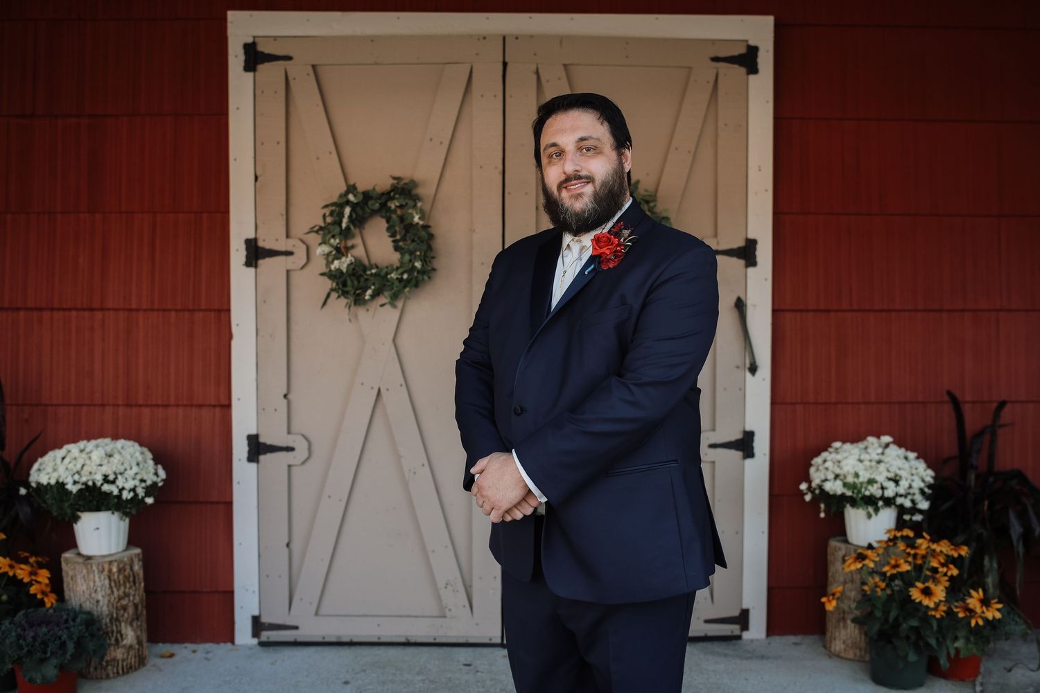A rustic barn wedding venue with white barn doors, decorative wreaths, and elegant floral arrangements.