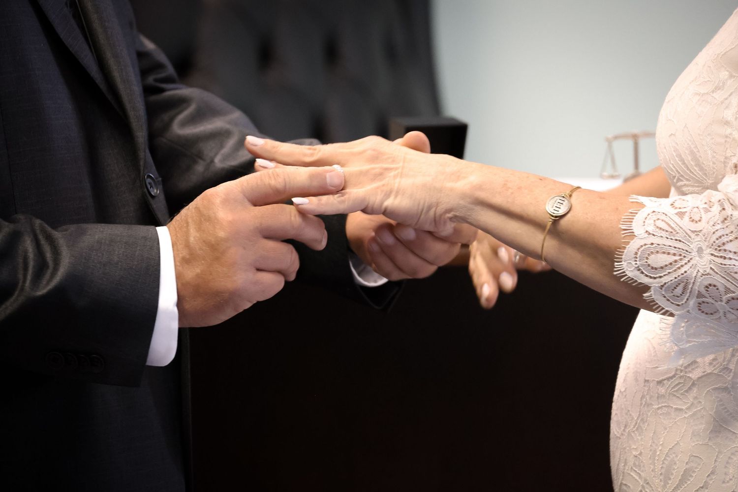 Close-up sequence of hands exchanging wedding rings during a traditional marriage ceremony.