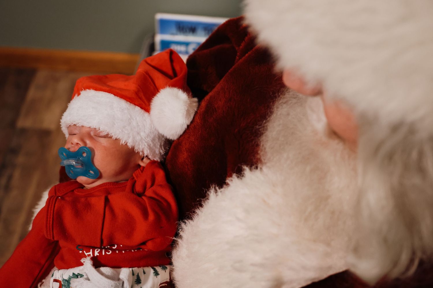 A small child in a red Santa outfit sits near someone wearing a white furry Christmas costume.