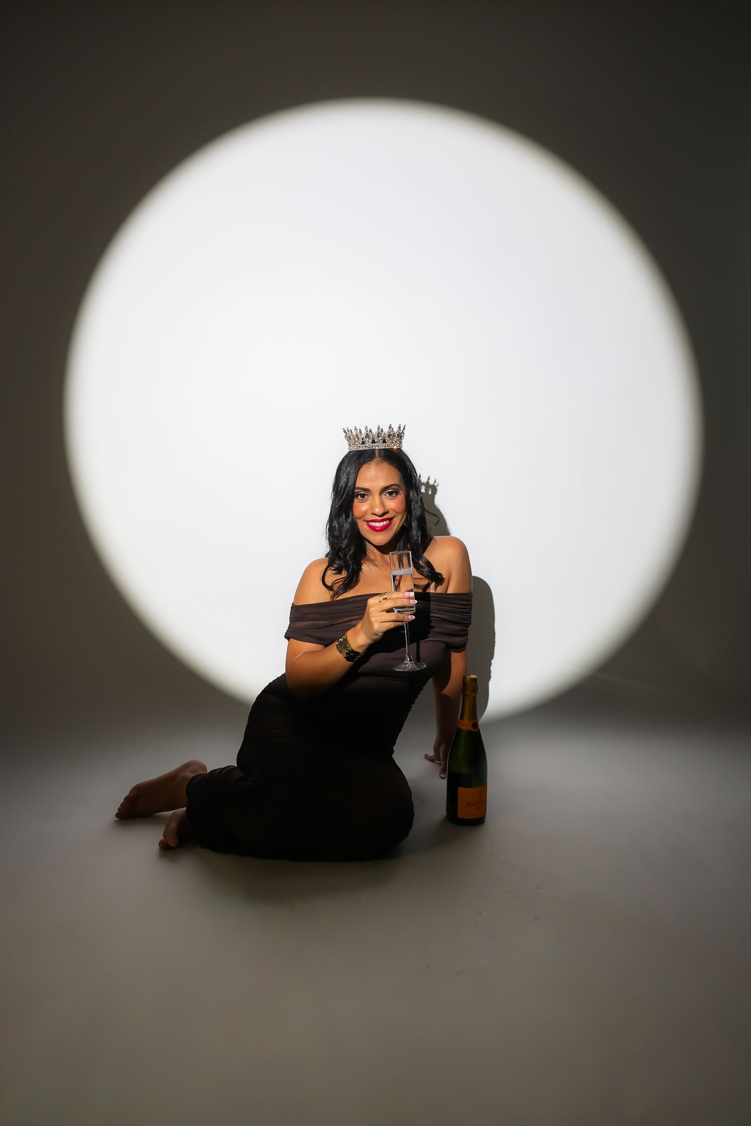A series of artistic black and white photos showing a figure in a black dress posing gracefully against a white spotlight.