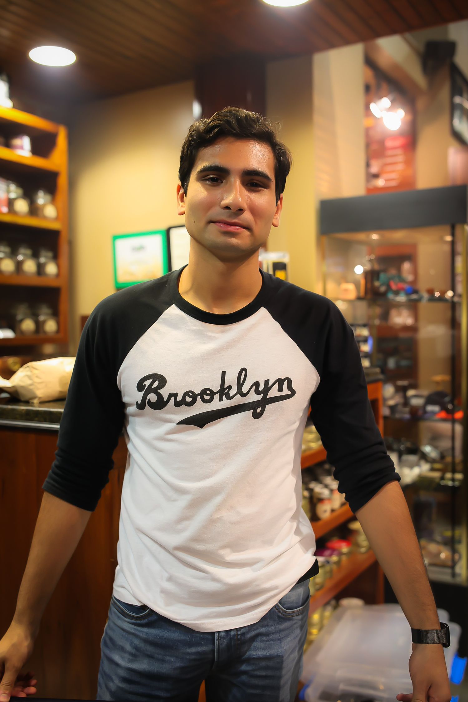 A person wearing a black and white baseball-style t-shirt poses in what appears to be a retail store setting.