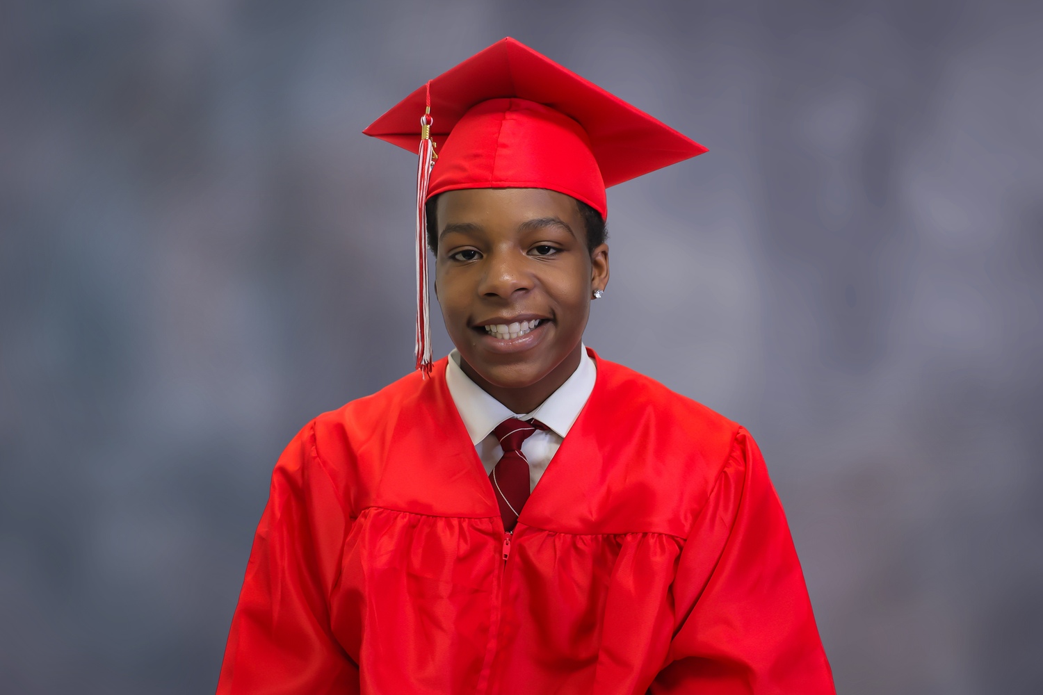 A series of graduation portraits showing graduates in bright red caps and gowns against a grey background.