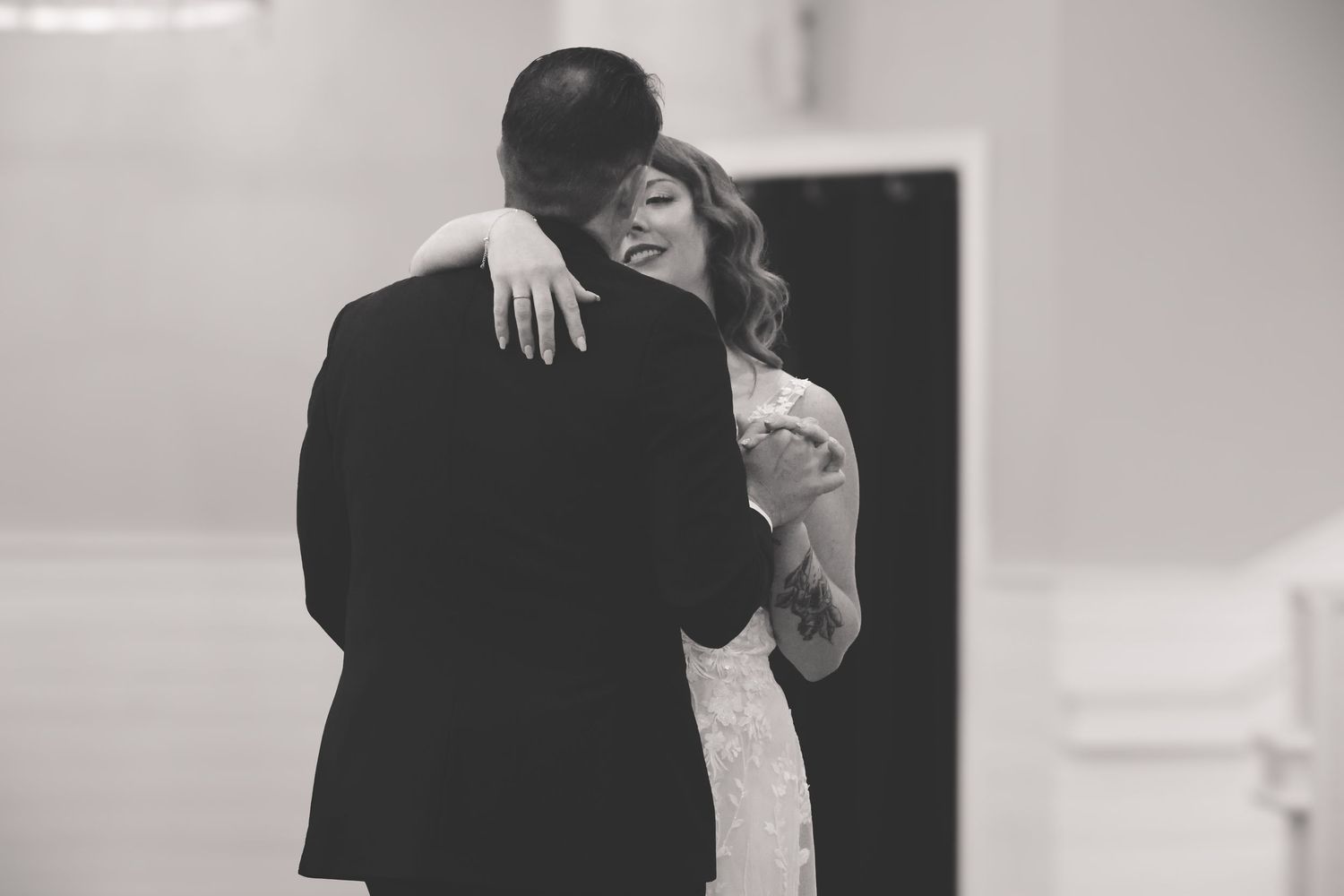 A tender black and white wedding moment captured as a couple embraces during their first dance.