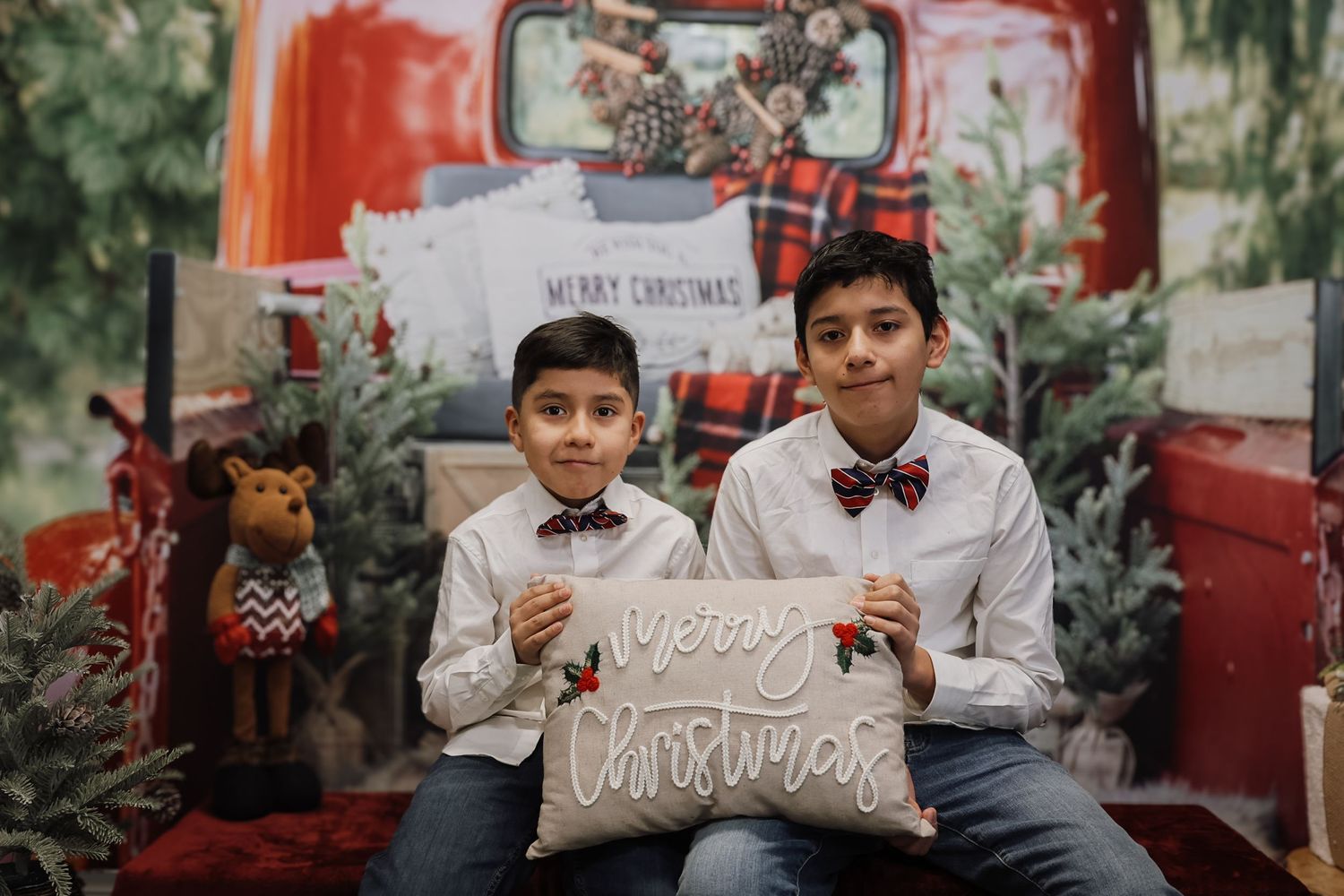 A festive red vintage truck decorated with Christmas trees and holiday decor creates a charming seasonal scene.