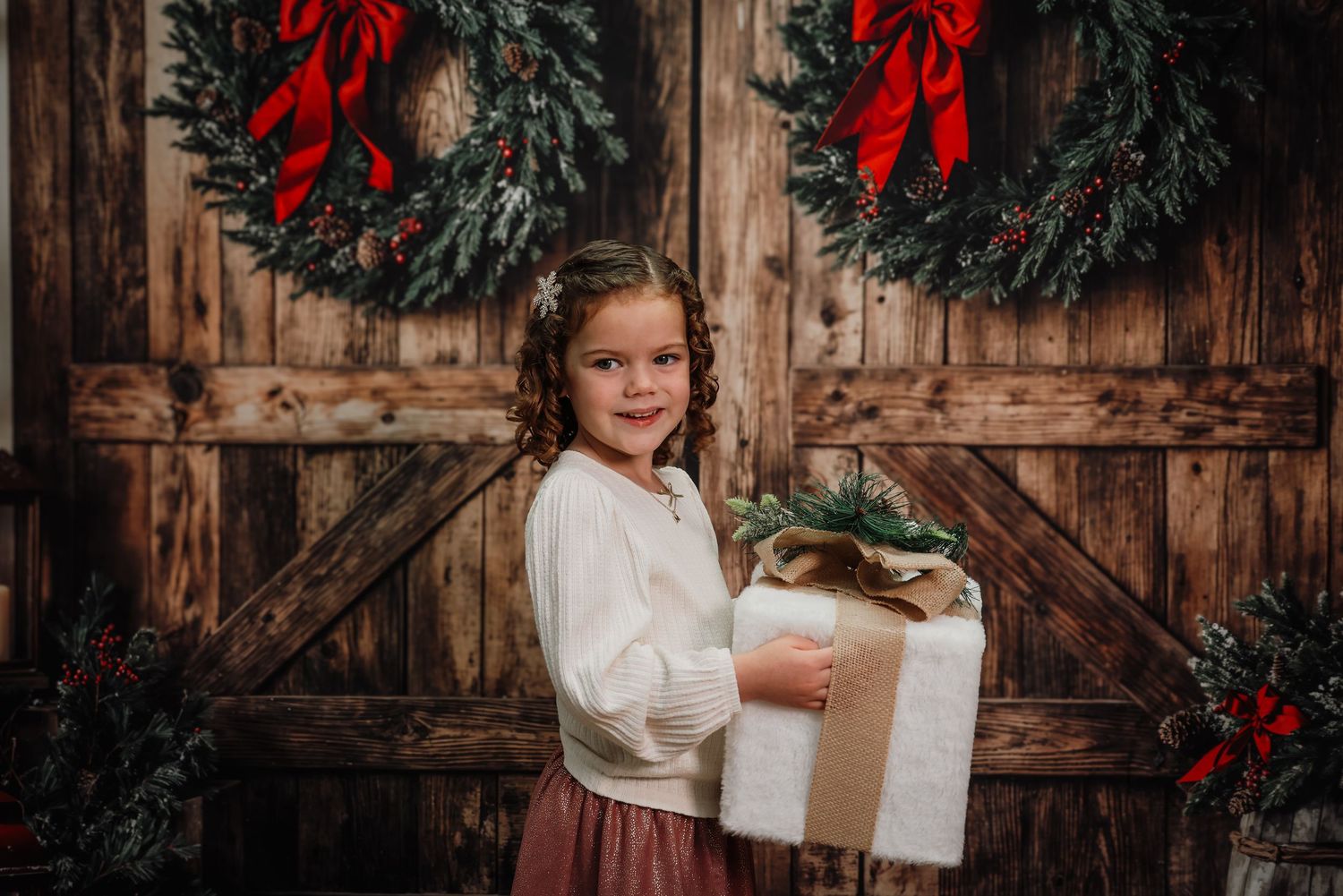 A series of Christmas portraits against a rustic wooden backdrop with evergreen wreaths and red bows.