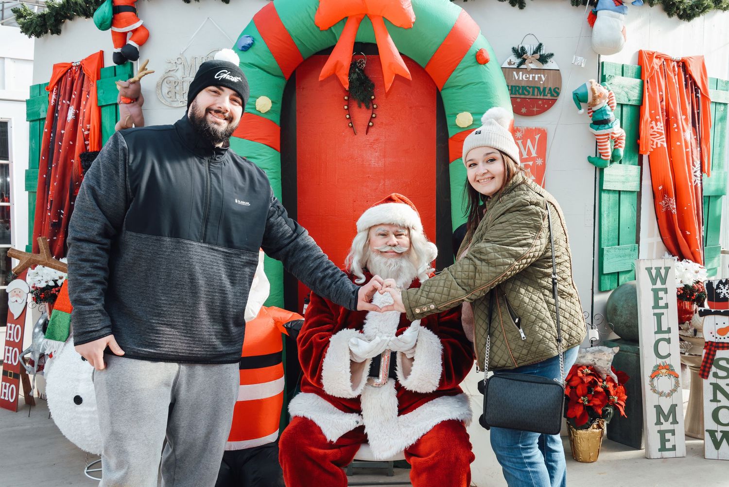Row of outdoor Christmas decorations including inflatable Santa Claus and snowmen in front of a retail store.