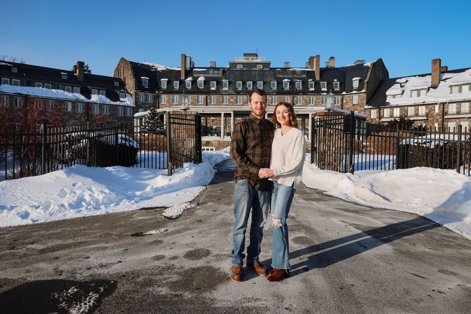 People enjoying a snowy winter day at a historic stone building complex with snow-covered grounds and walkways.