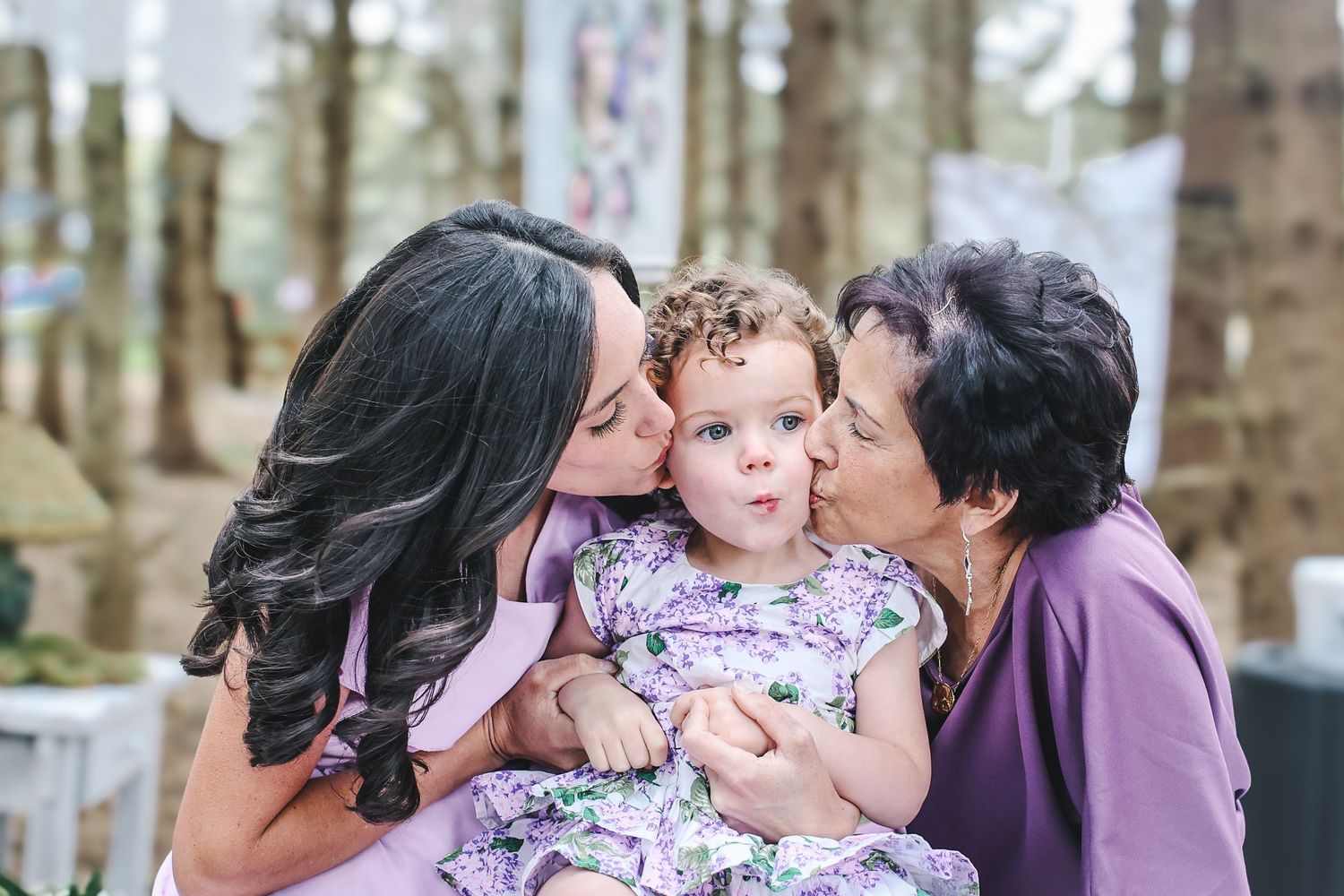A series of candid outdoor family moments showing affectionate kisses and embraces in a wooded setting.