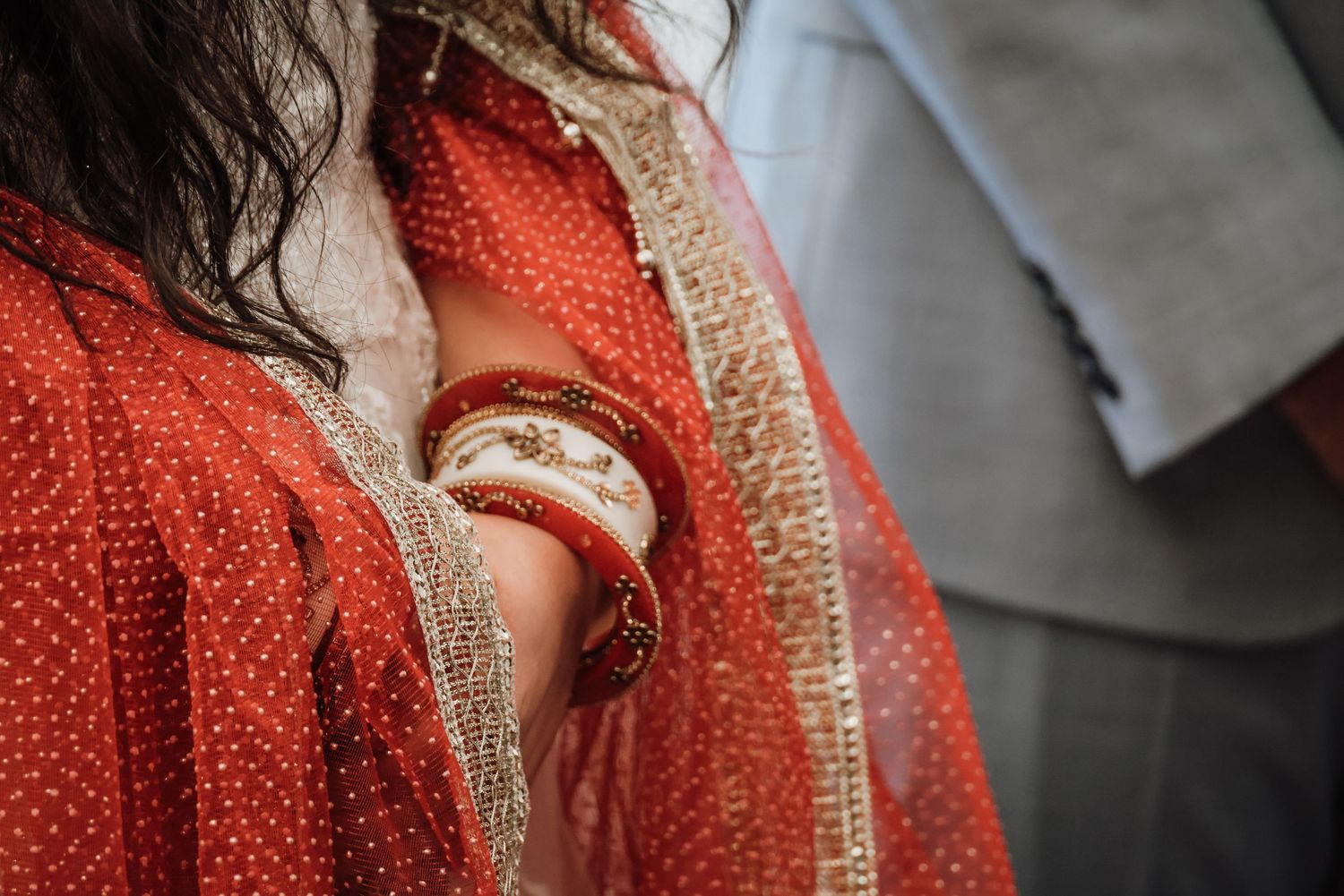 Close-up detail of a red knitted sweater with beige trim showing textural pattern and stitching.