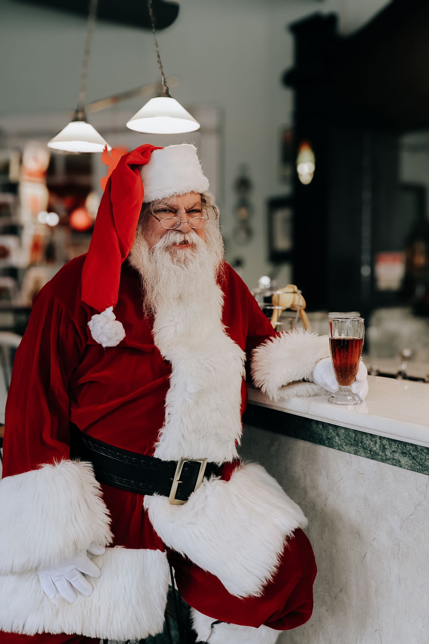 A person in a traditional red and white holiday costume sits at a counter in a casual indoor setting.