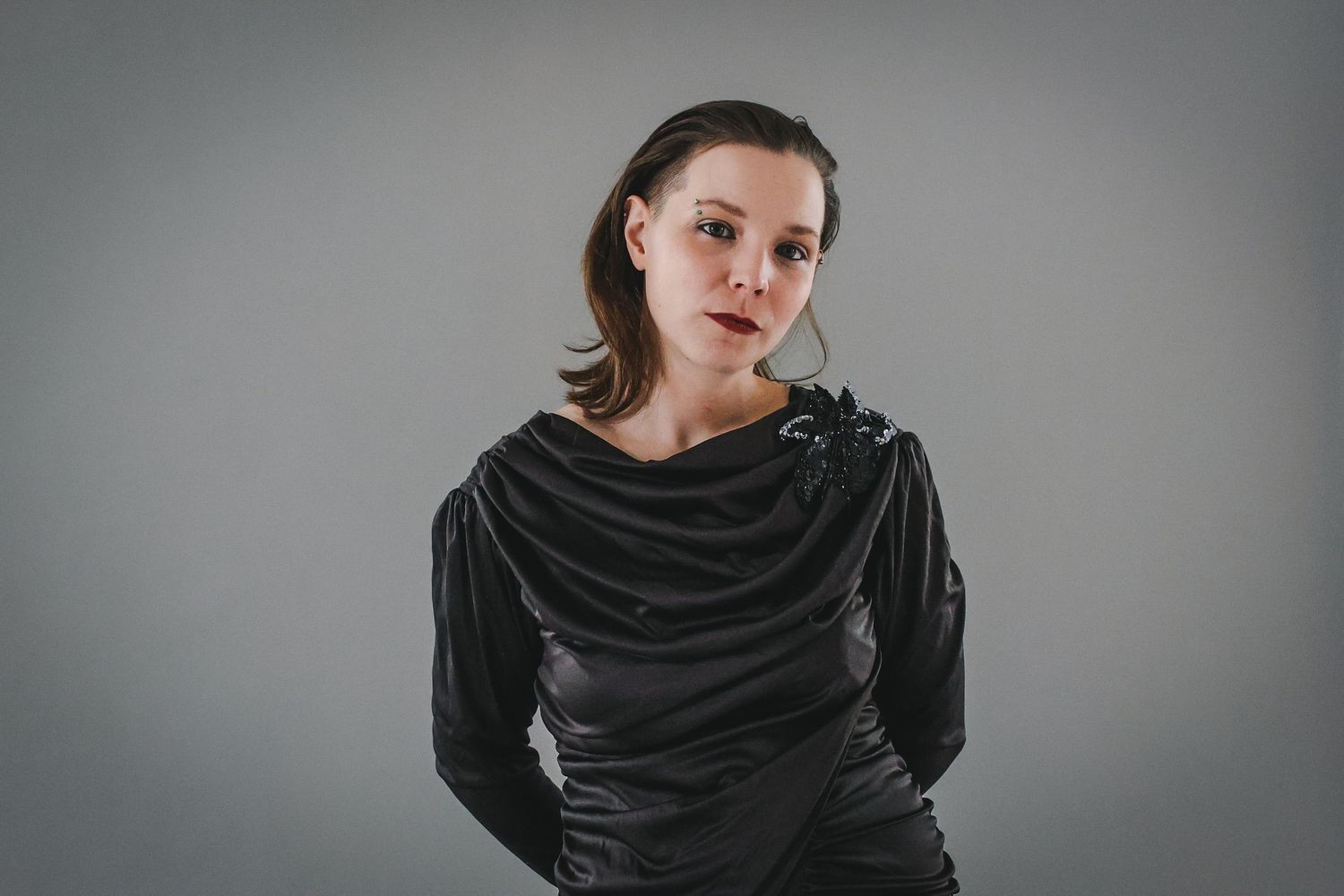 A series of six black and white portraits showing a figure wrapped in dark fabric against a gray background.