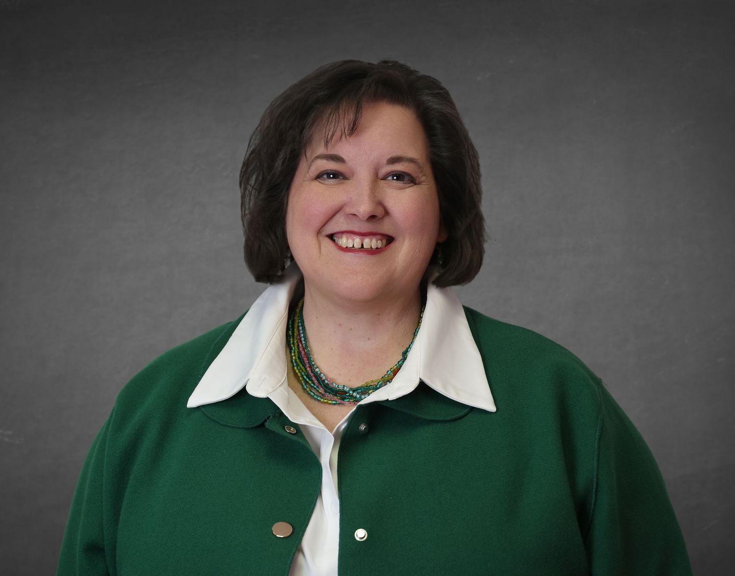 A series of professional headshots showing someone in a green blazer and white collar against a gray background.