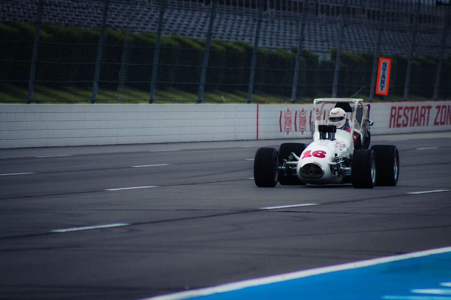 Formula One race car speeds down a wet track during a rainy motorsport competition.
