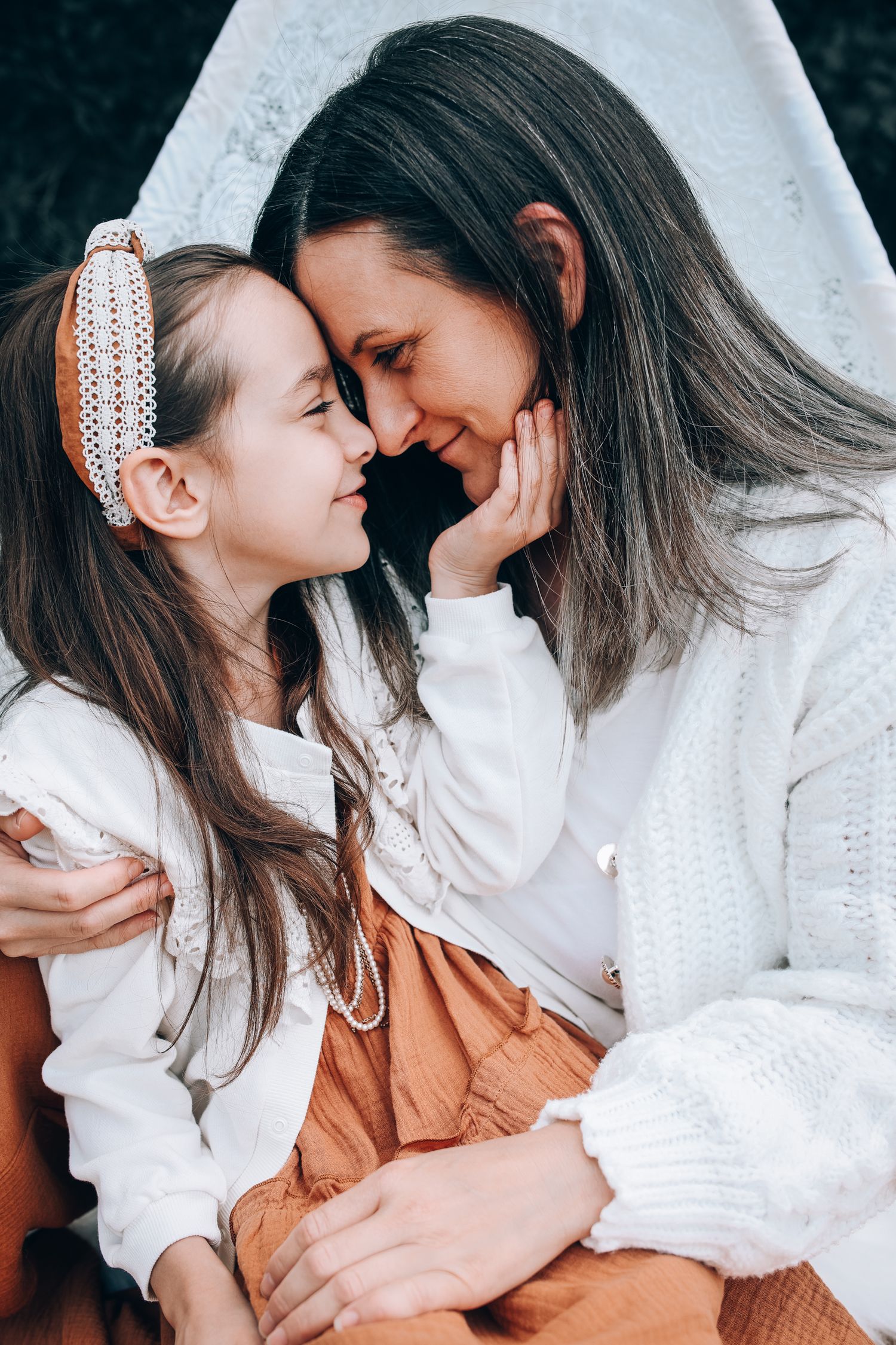 A touching intimate moment of affection and bonding between a parent and child dressed in white and orange.