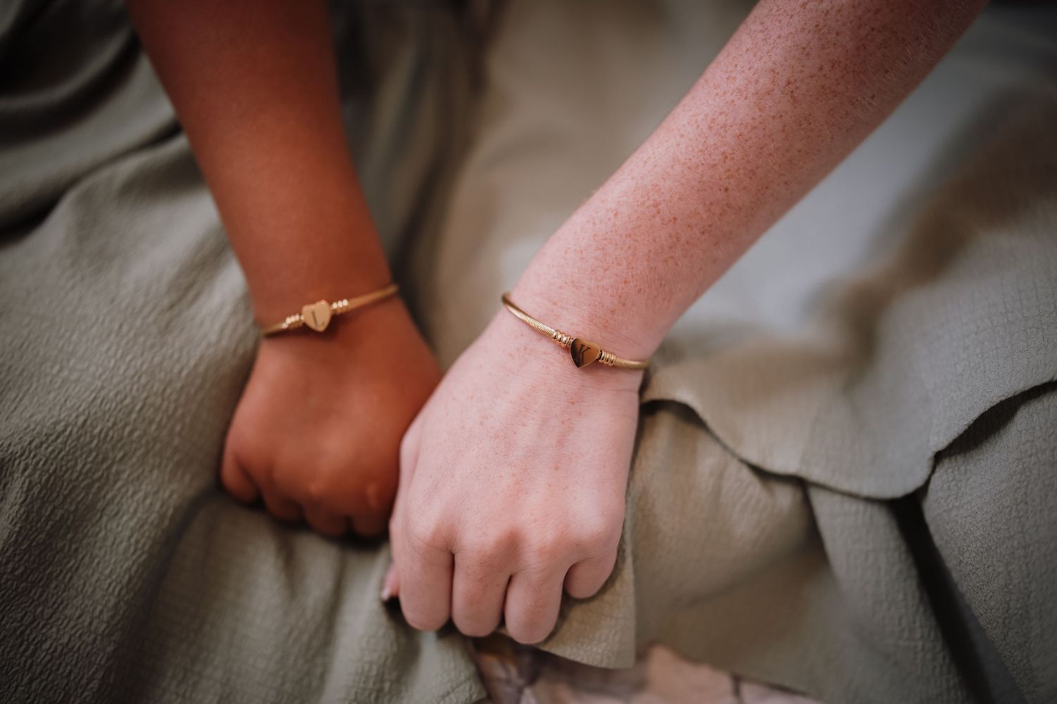 Close-up view of hands wearing delicate gold rings with minimalist designs against a neutral background.