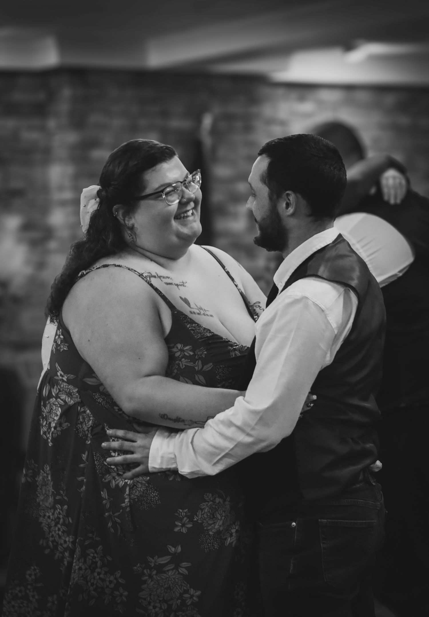 A joyful couple shares a romantic dance moment together at a wedding reception in black and white photography.