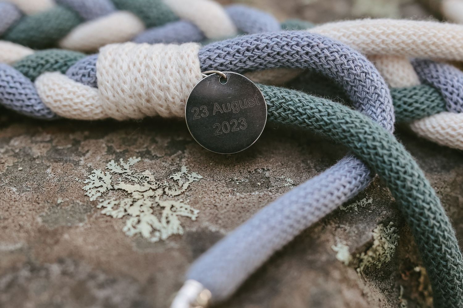 Close-up macro photo of a knitted or crocheted fabric texture in gray and green colors showing intricate stitch details.