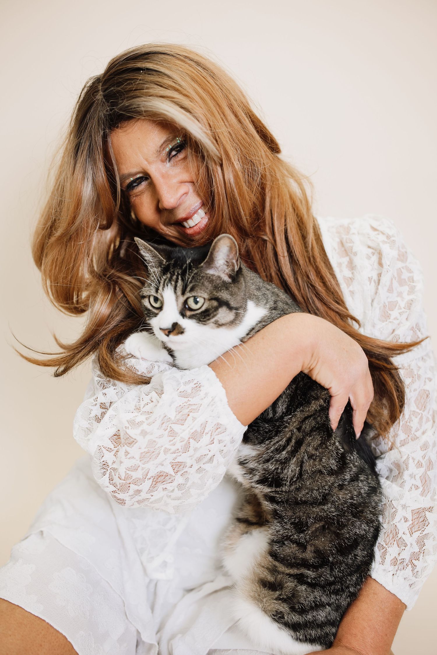 A series of photos showing a person in white lace holding and cuddling with a gray tabby cat.
