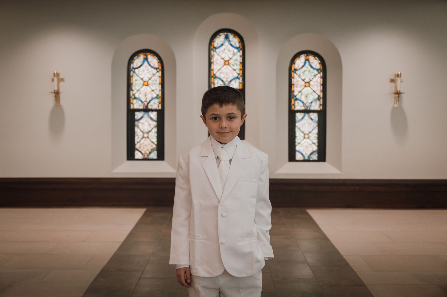 A church interior with stained glass windows and wooden pews creates an elegant setting for a wedding ceremony.
