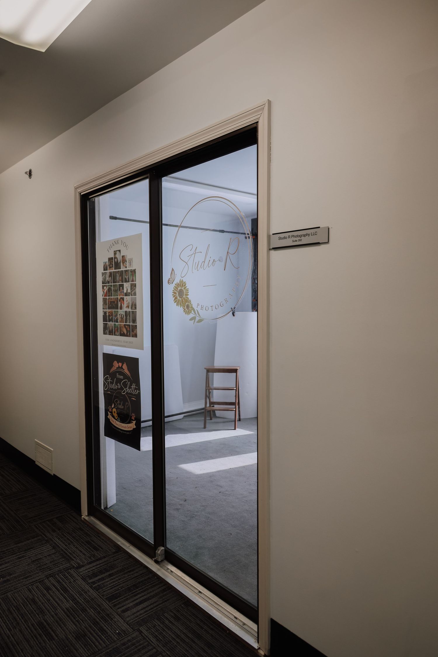 Interior office hallway with dark carpeting shows glass doors and windows leading to empty commercial spaces.