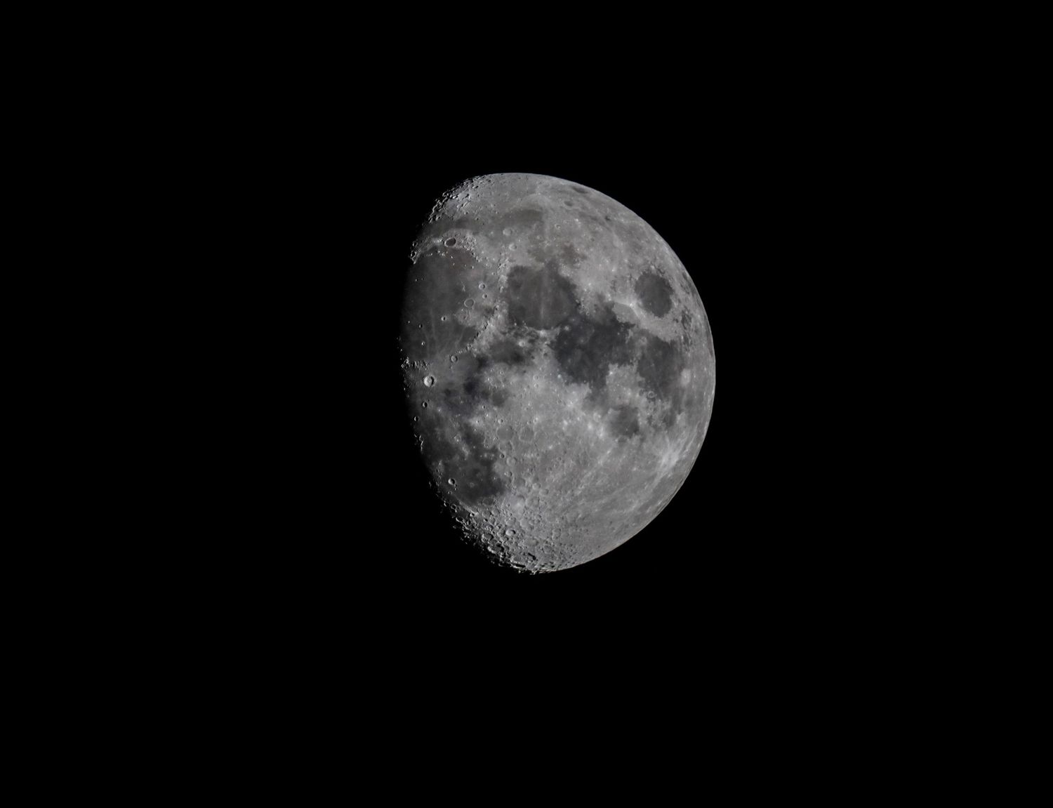 A detailed photograph of a waxing gibbous moon against a dark black night sky, showing visible craters and surface details.
