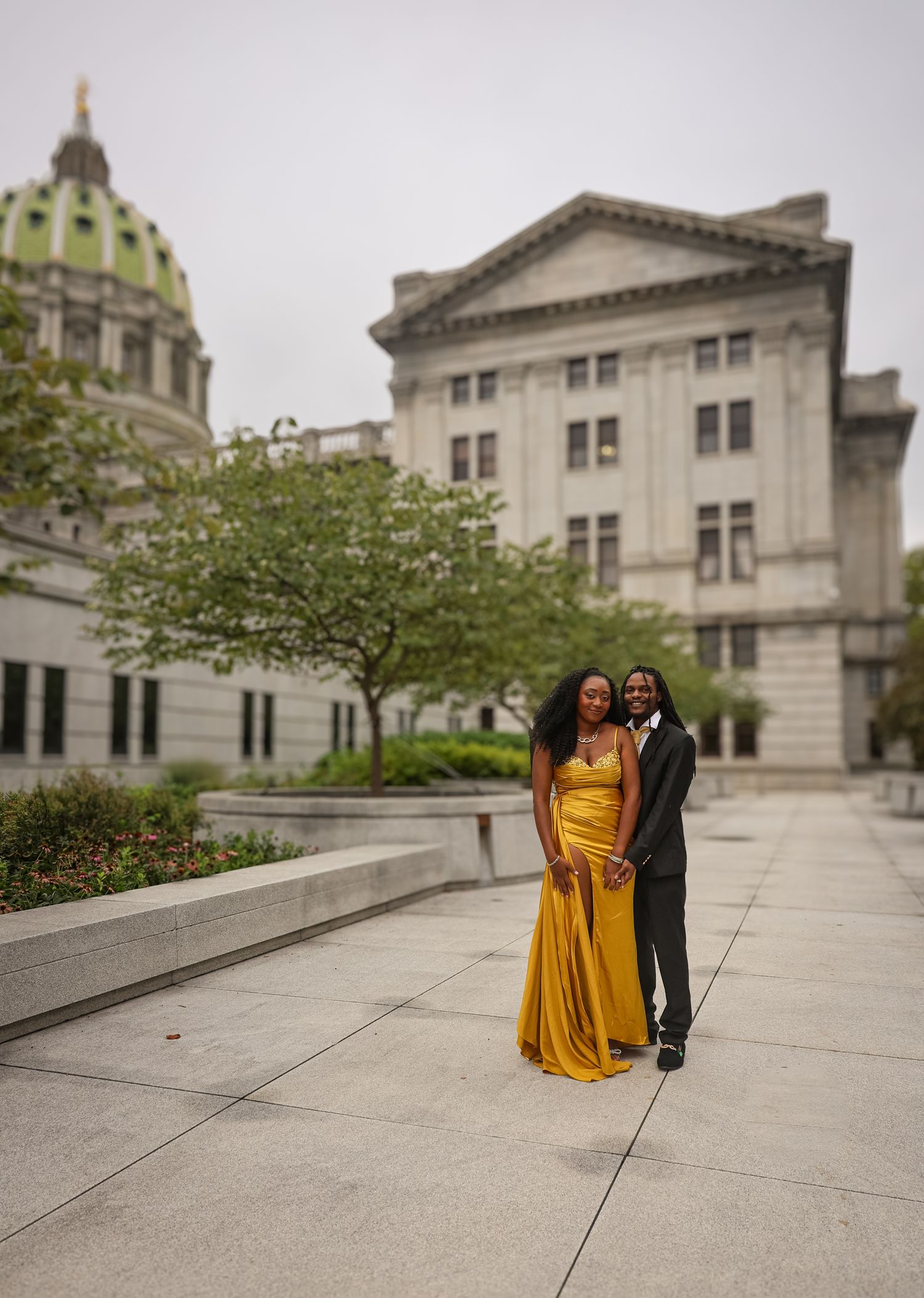 A couple poses together on an elegant stone terrace with classical architecture in the background.