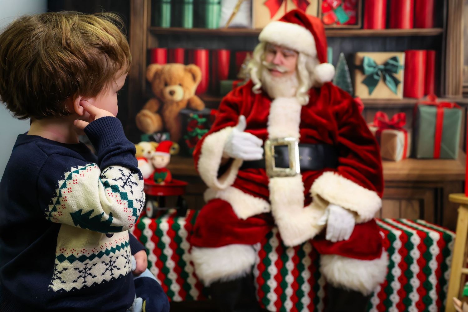 A festive holiday scene with Santa Claus in his traditional red suit greeting visitors in a decorated retail setting.
