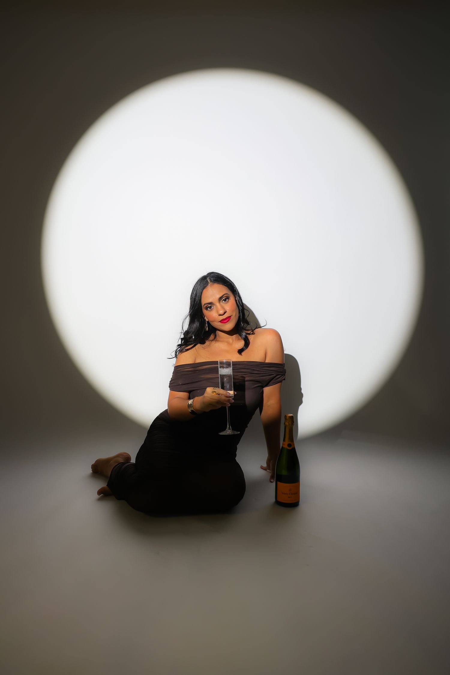 A creative sequence of dramatic spotlit poses showing someone in black against a dark background with a beverage.