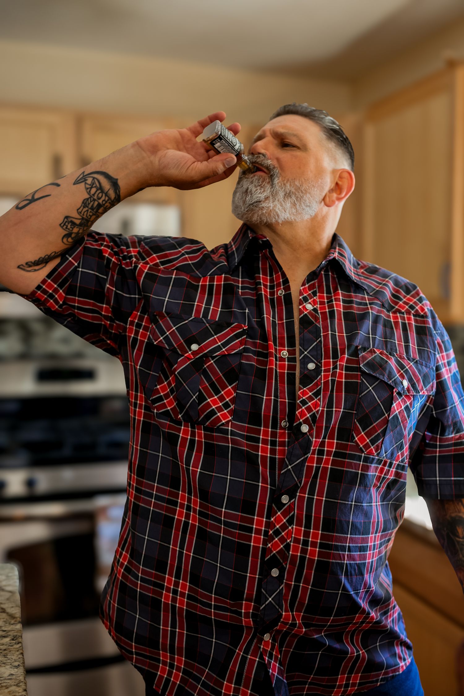 Person in plaid shirt takes a drink from a glass in a sequence of progressive sipping motions.