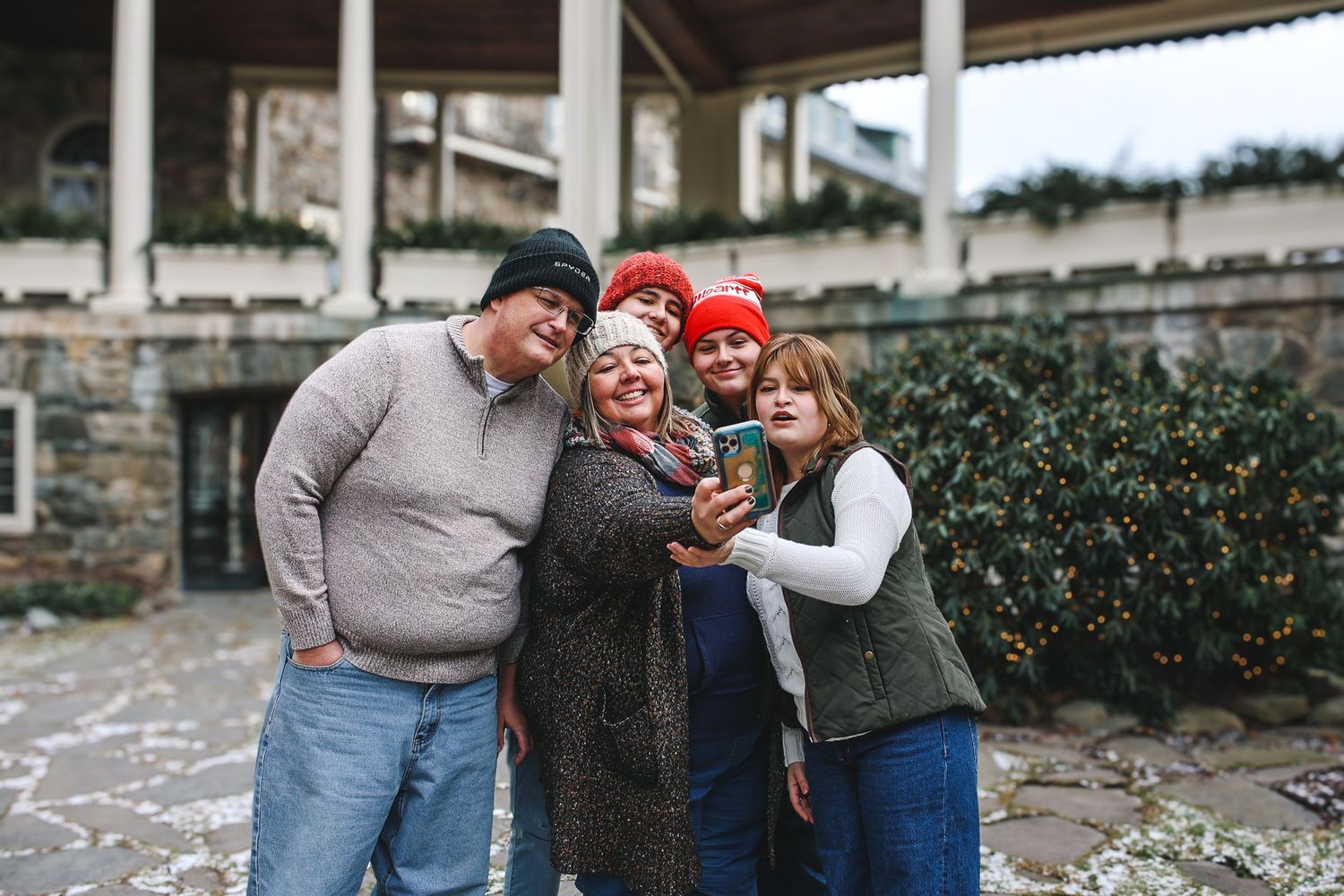 Three people in casual winter attire share a joyful moment together while posing outdoors.