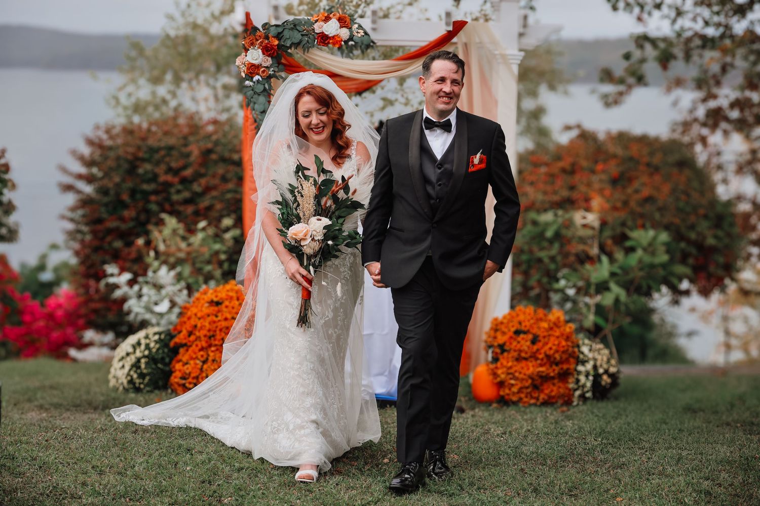 Autumn wedding celebration with vibrant orange maple trees and white florals creating a stunning seasonal backdrop.