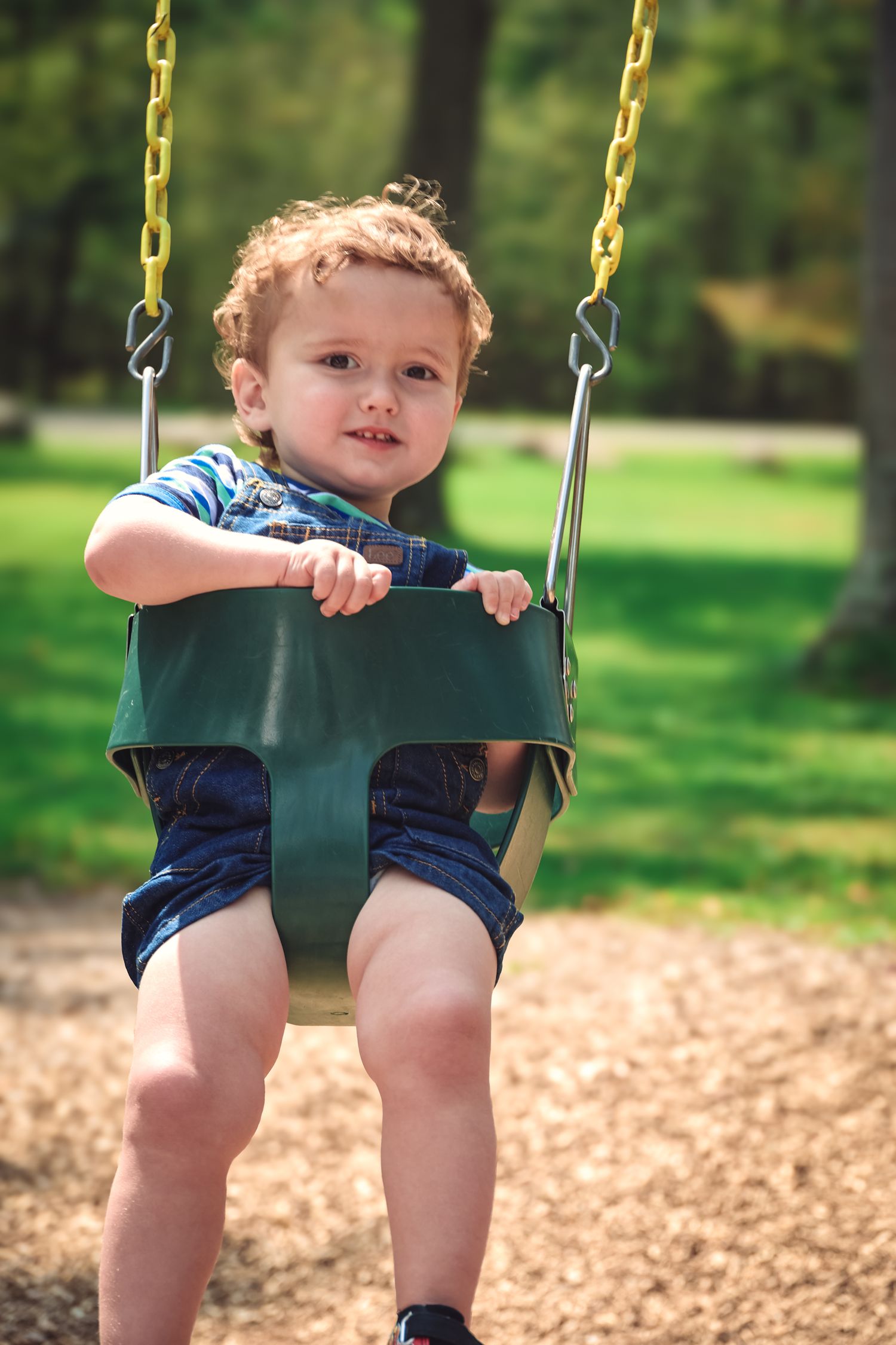 A sequence of four photos showing a small child swinging in a green playground swing on a sunny day.
