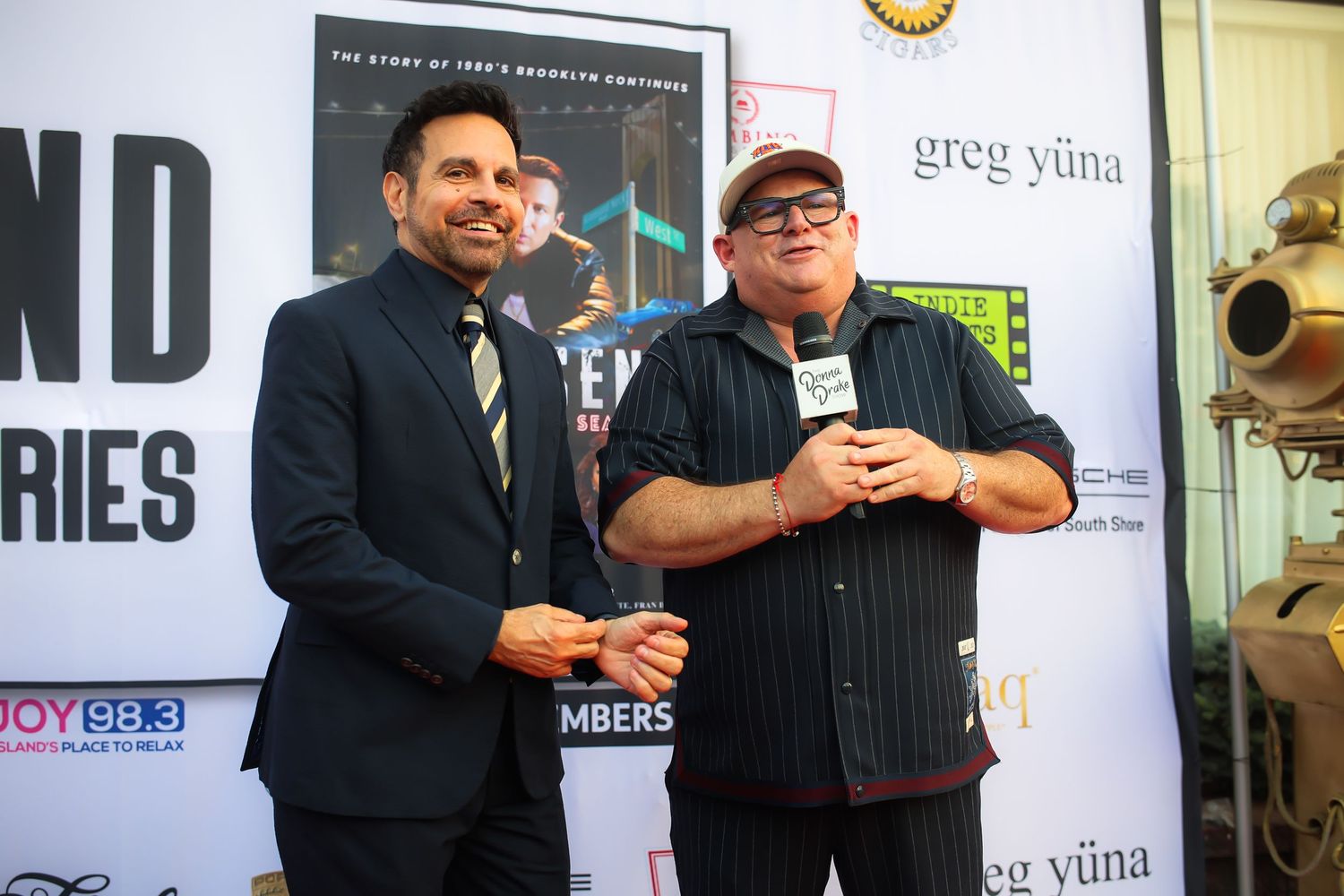Two people in dark suits standing together and conversing at a professional event.