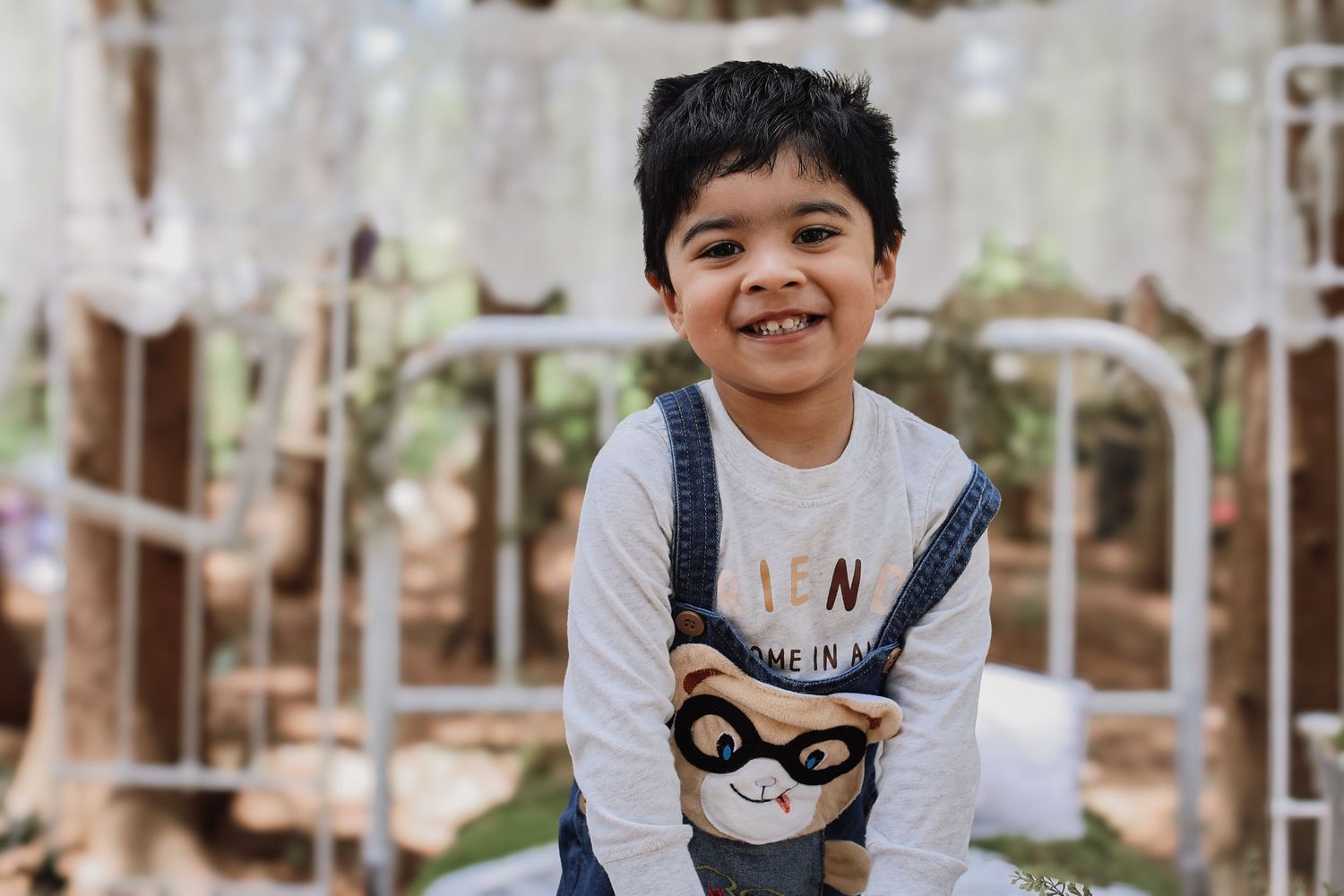 A series of five photos showing a child playing outdoors in a natural setting with trees and wooden structures.