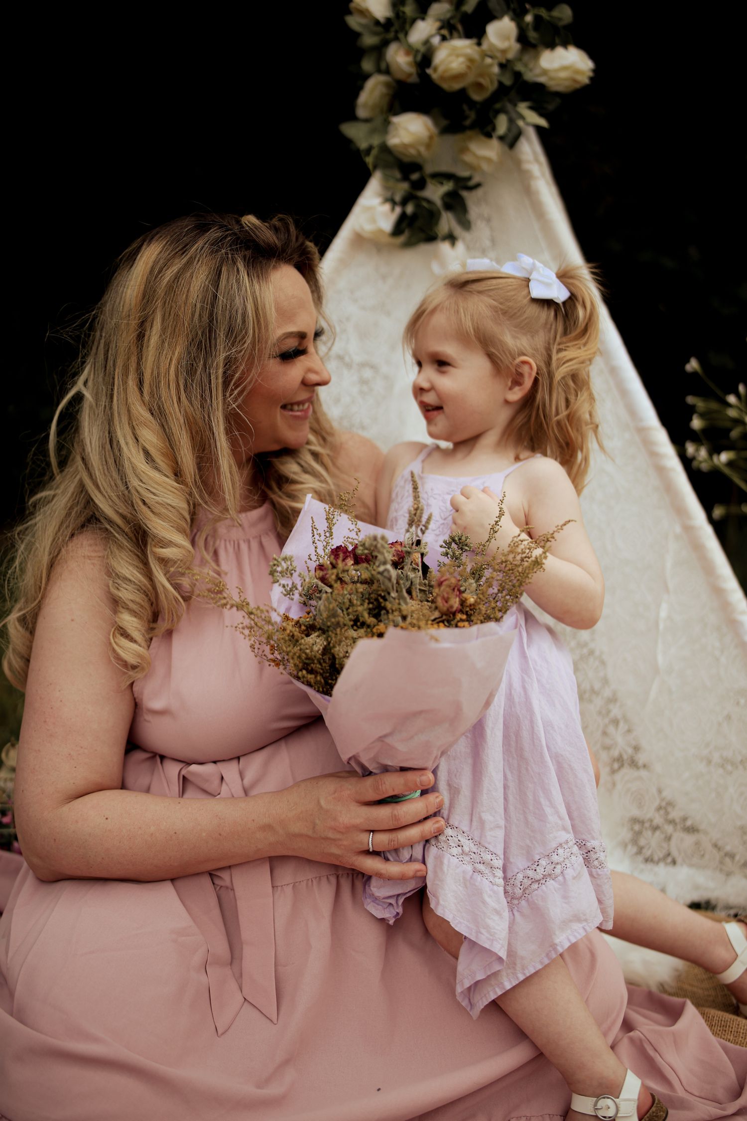 A tender moment captured in pink dresses against a white backdrop with rustic floral bouquets.