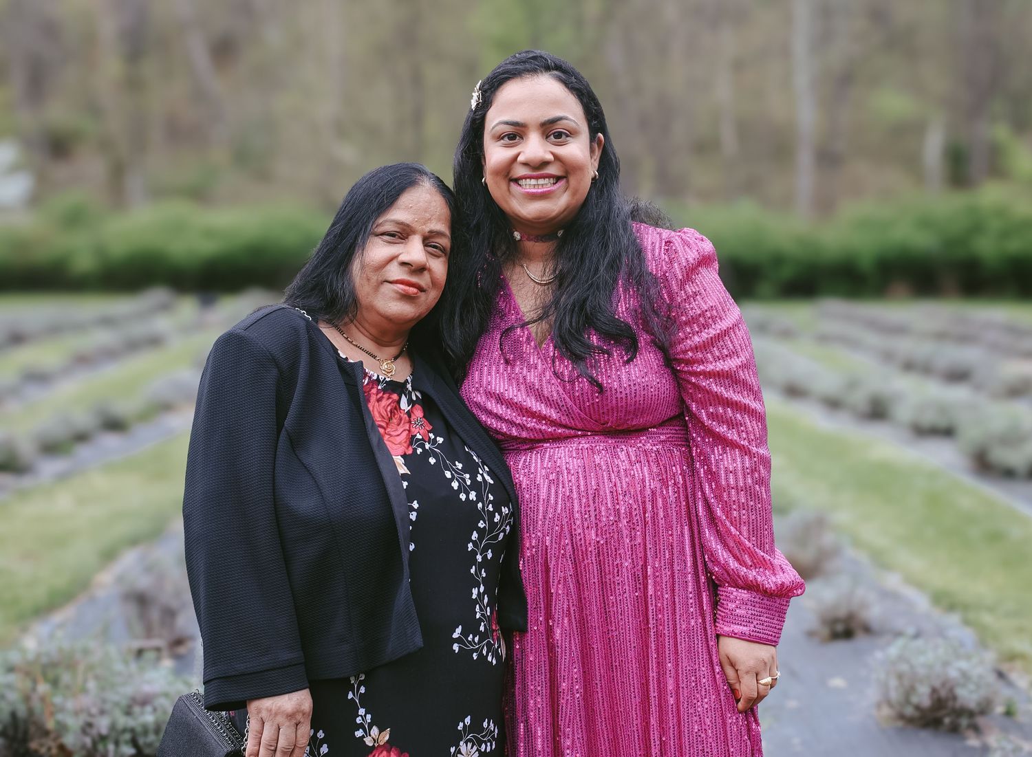 Two people in festive attire smile together outdoors against a natural landscape background.