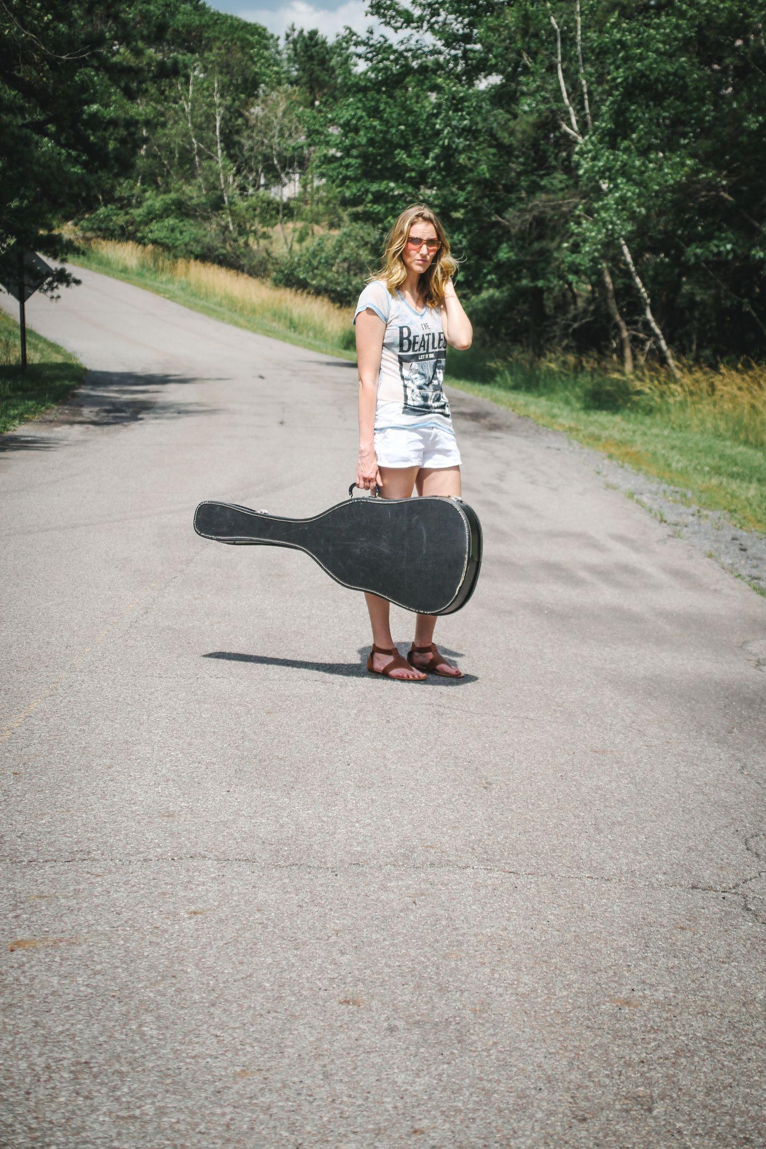 A sequence of photos showing a guitar case being placed on a paved forest path during a sunny day.
