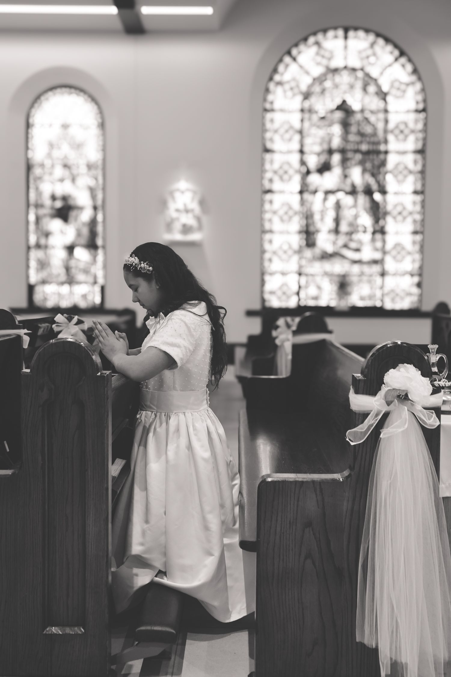 A sequence of black and white photographs showing a christening gown displayed in a church with stained glass windows.