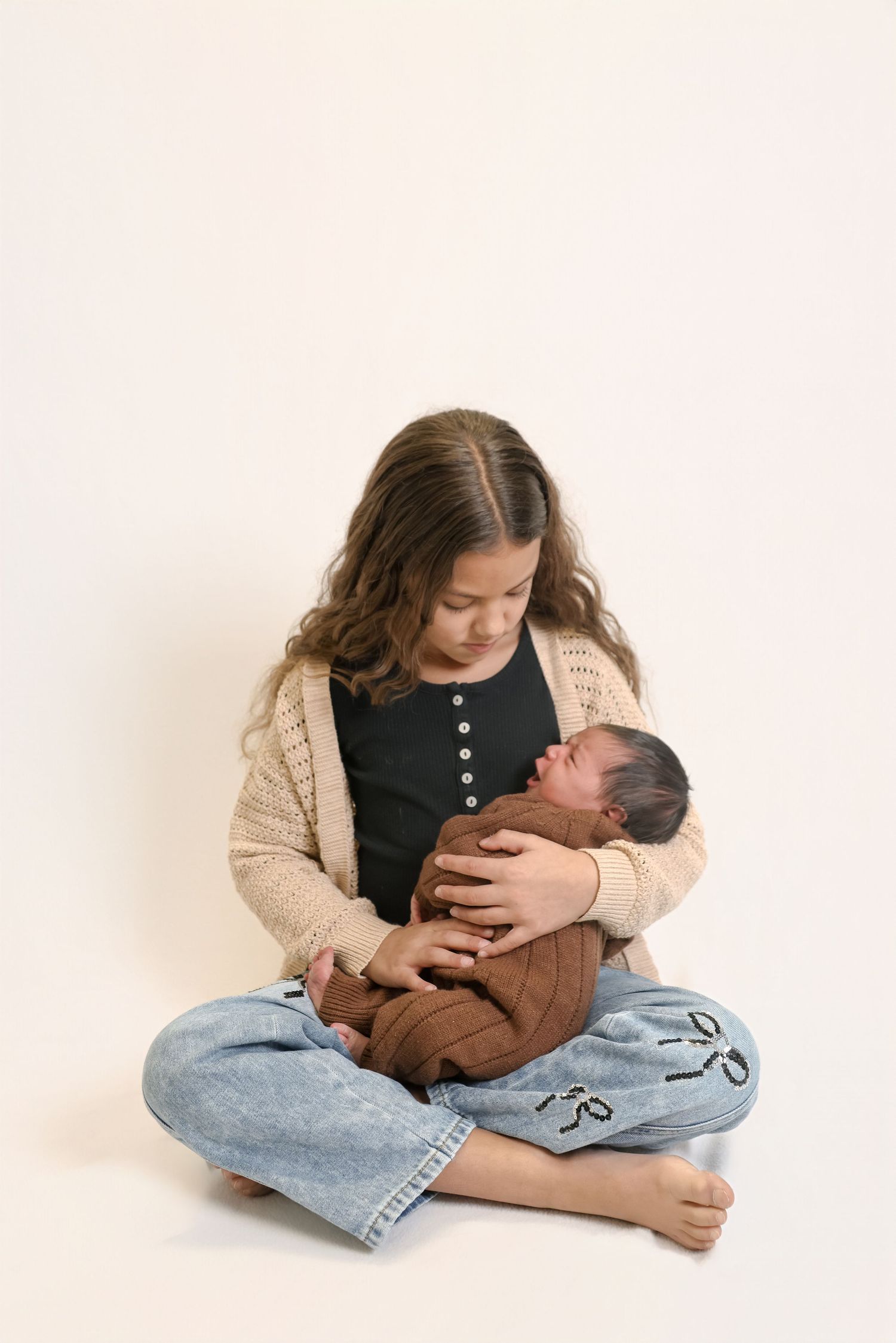 A tender moment captured in a series of photos showing someone cradling a baby while sitting in casual denim jeans.